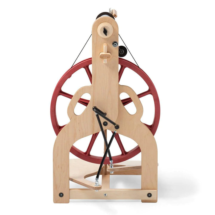 A rear perspective of the Ladybug Spinning Wheel illustrates the wheel's Scotch tension, double drive, and bobbin lead features. The image highlights the wheel's functional yet stylish construction, complete with accessories like the travel bobbins and whorls that support a range of yarn spinning techniques for the fiber enthusiast