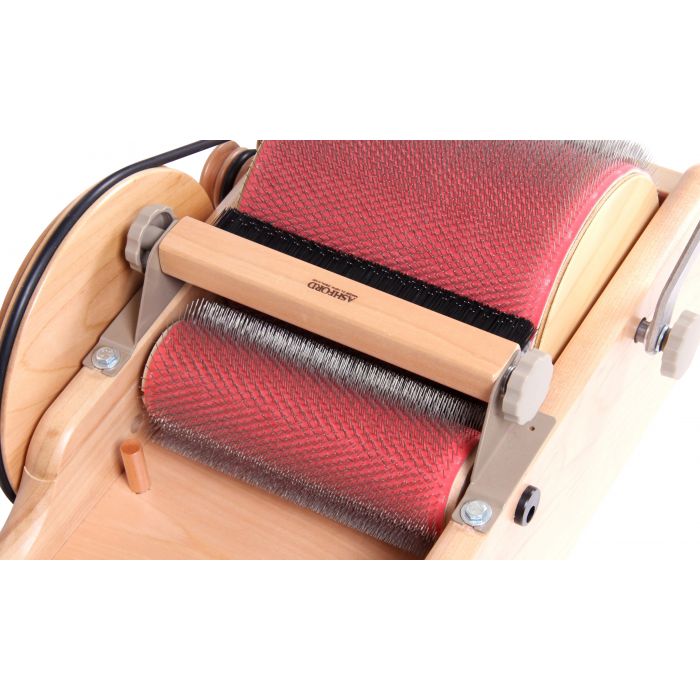 Ashford packer brush kit installed on a drum carder, pressing fiber into the large drum.