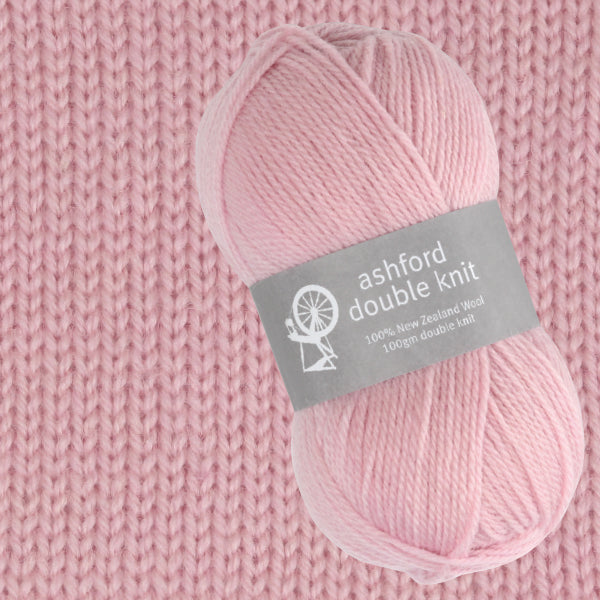Ball of pink yarn with 'ashford double knit' label on a knitted fabric background