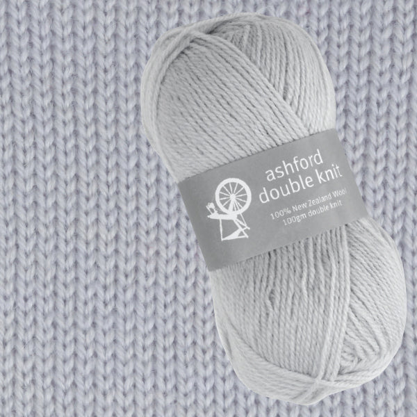 Ball of gray ashford double knit yarn on a knitted fabric background