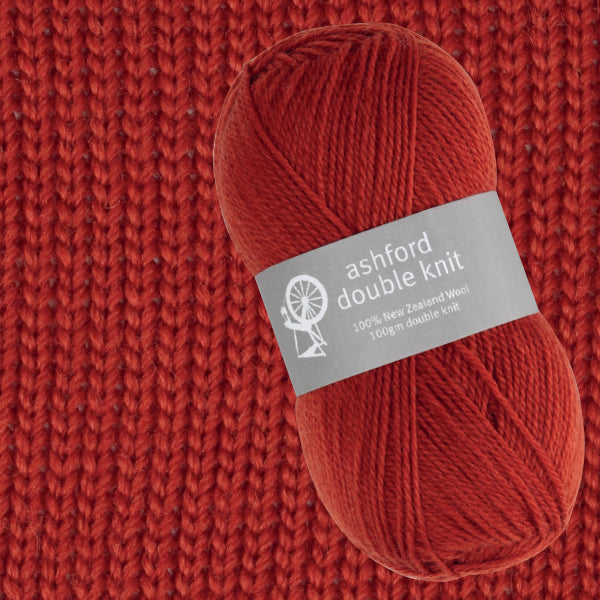 Red yarn ball with 'ashford double knit' label on a red knitted background