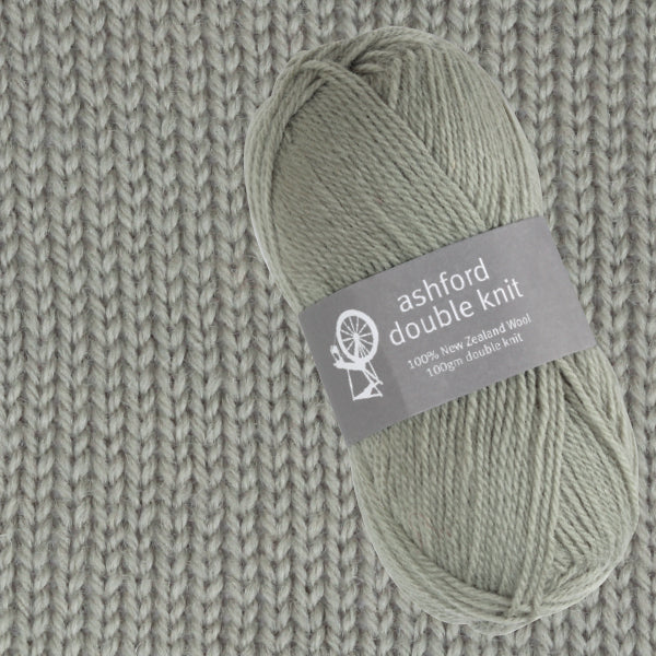 Ball of green yarn with an Ashford Double Knit label on a knitted fabric background