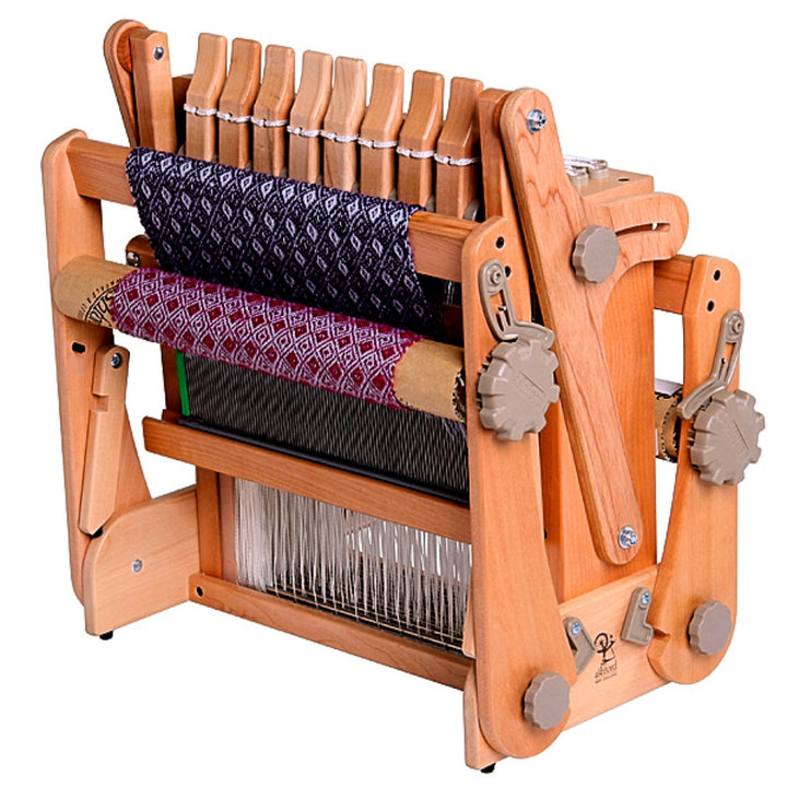 This image captures the Ashford Katie Table Loom folded, highlighting its space-saving and portable design. The loom's warm wooden finish and precision-crafted parts are visible, illustrating how it conveniently folds for storage or transport, making it ideal for weavers who appreciate efficiency and mobility.