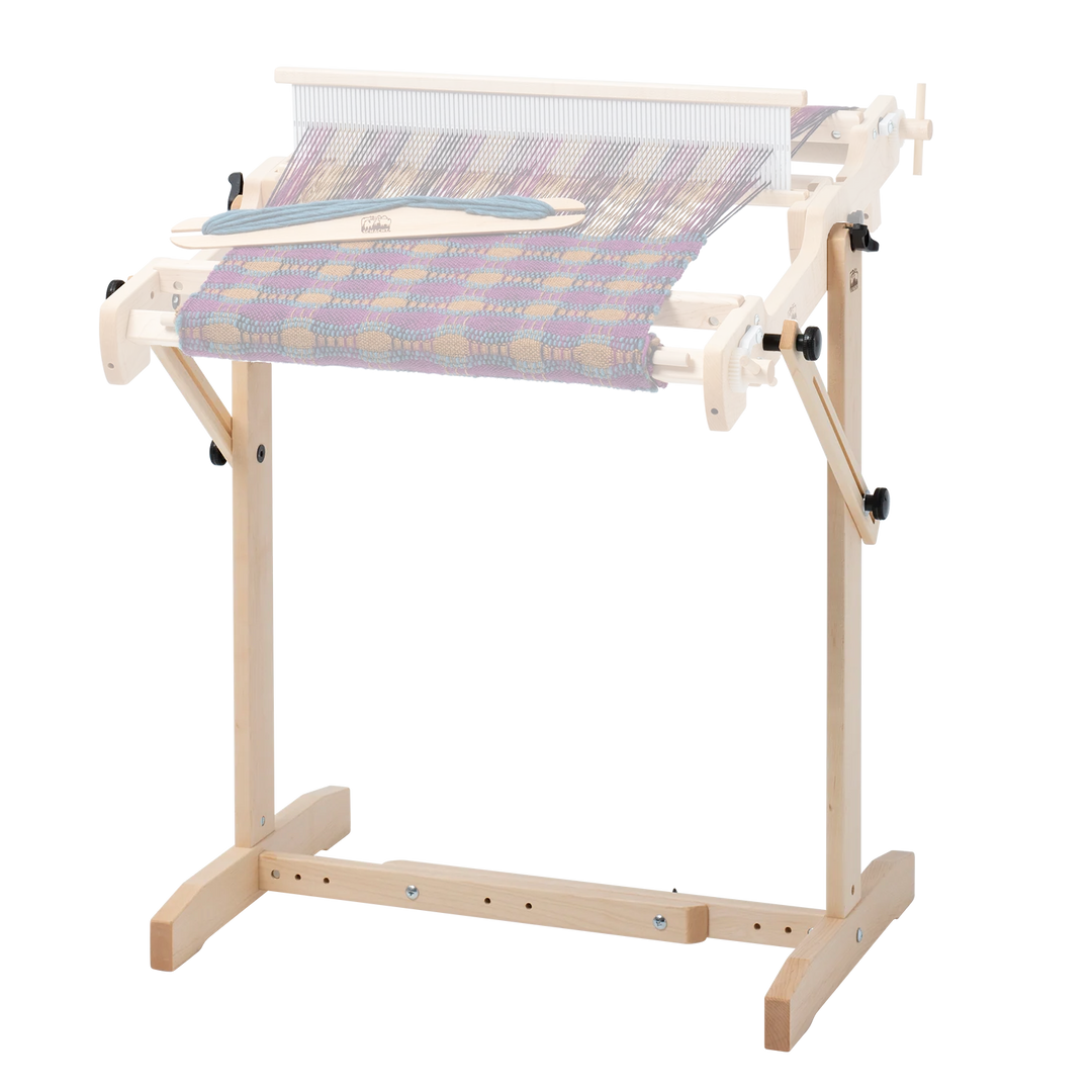 Wooden trestle loom stand with a Wooden Schacht Flip weaving loom attached on a plain background