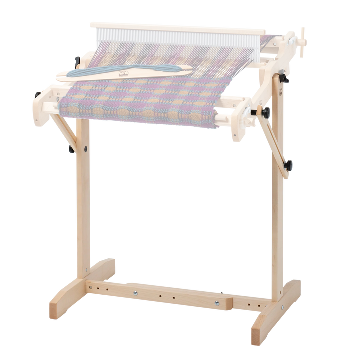 Wooden trestle loom stand with a Wooden Schacht Flip weaving loom attached on a plain background