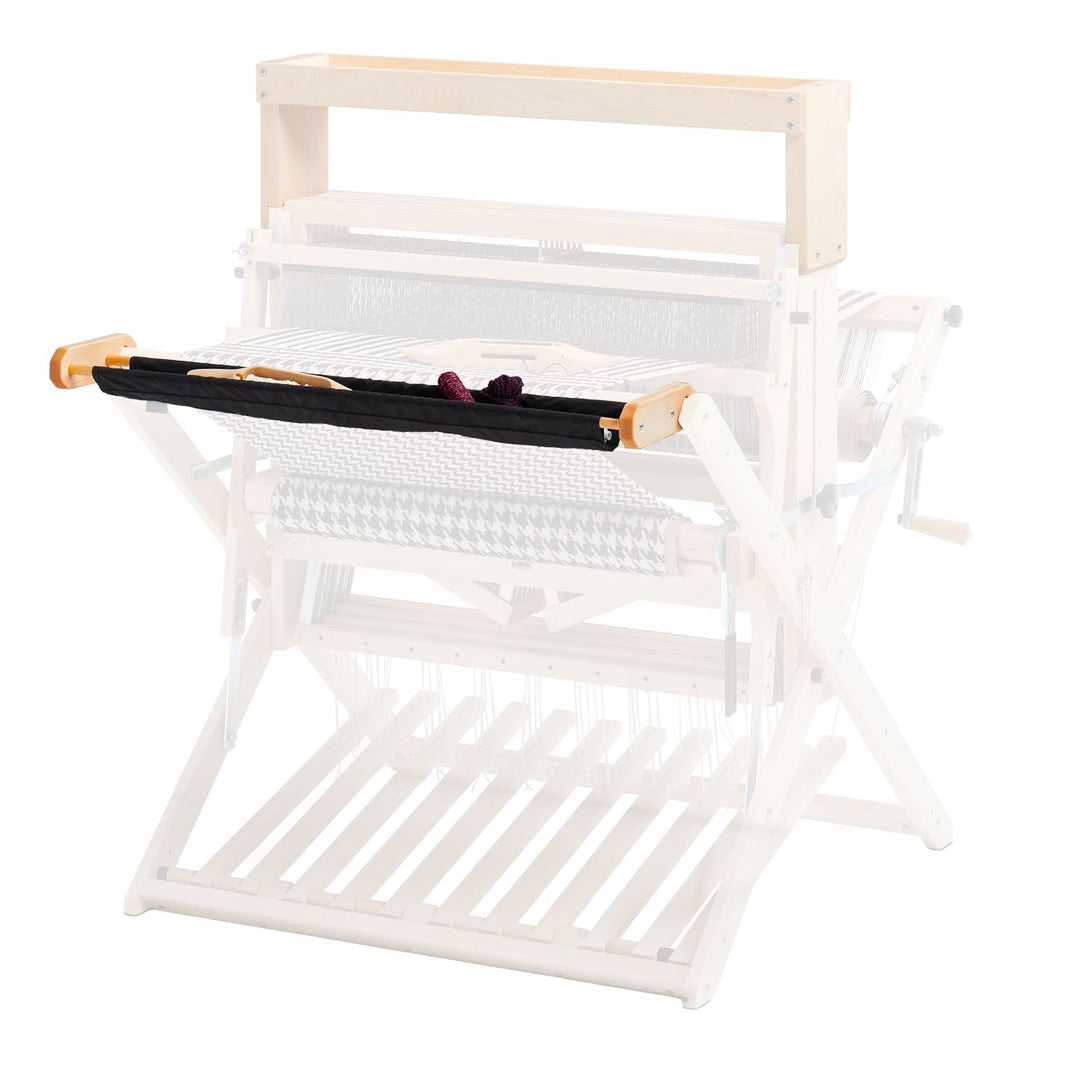 Black cloth tray attached to wooden weaving loom on white background